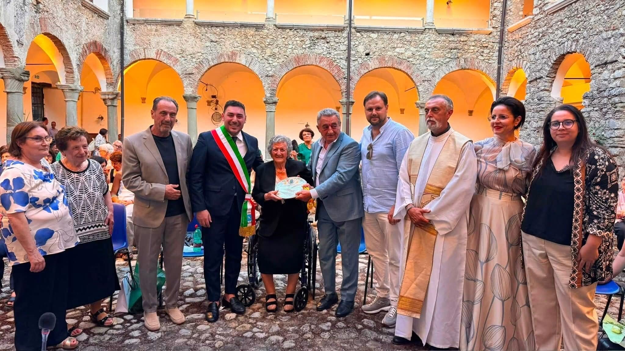 Una donna centenaria riceve una targa ricordo a Ottati in un evento di celebrazione della vita e della comunità